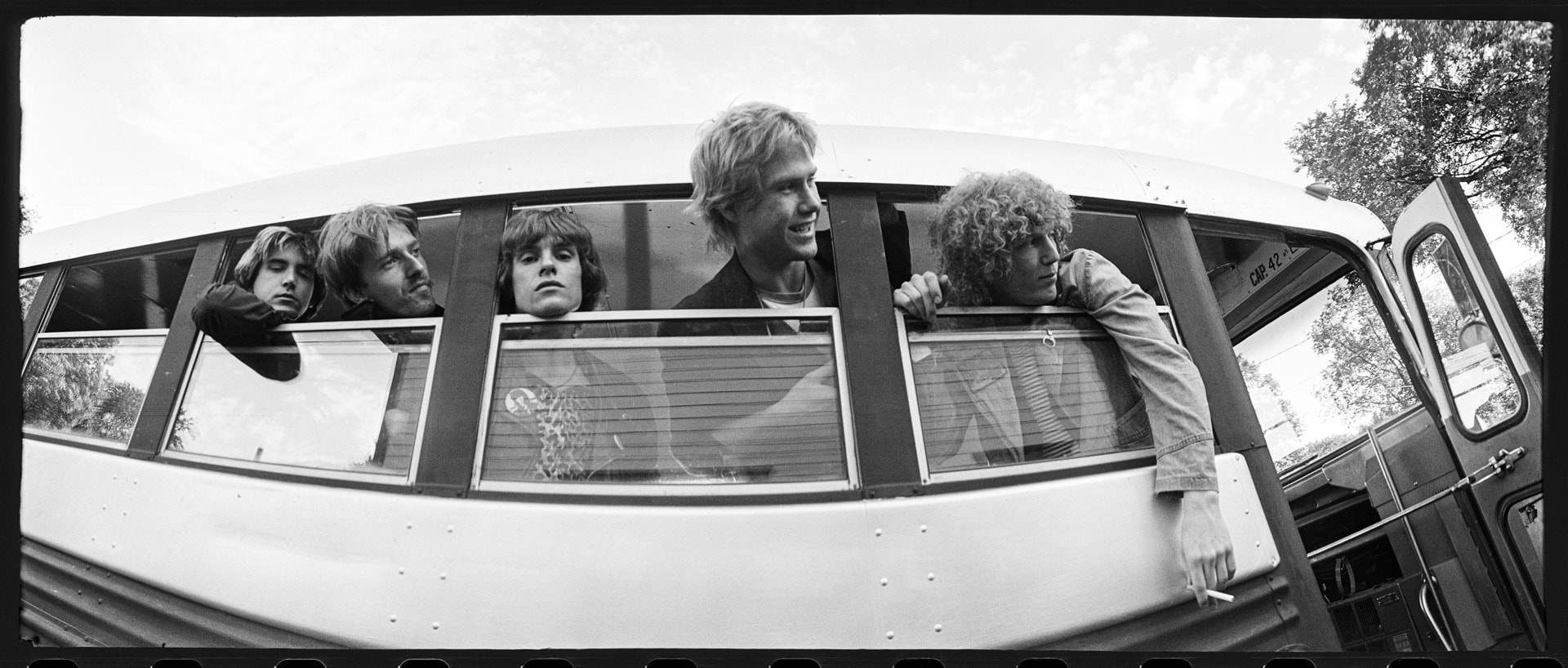 Photo of four men looking out the window of a bus.