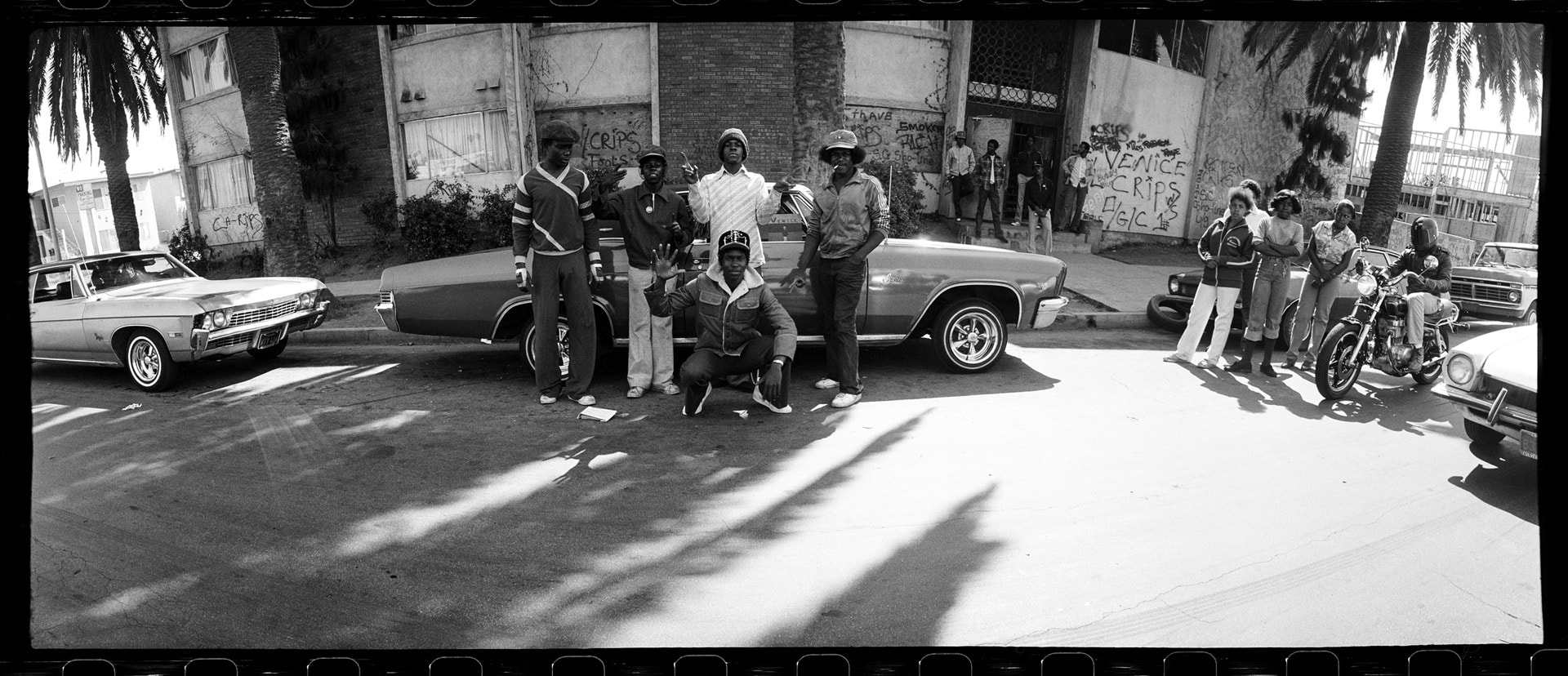 Photo of a movie set with several cars and people smiling