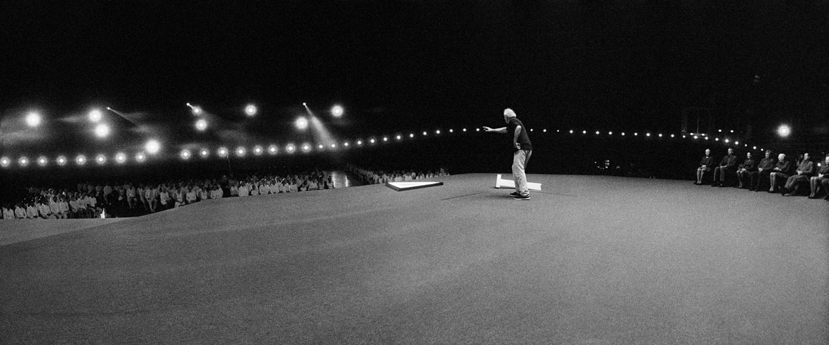 Widelux Photo showing a man on a stage in front of an audience.